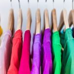 Fashion clothes on clothing rack – bright colorful closet. Close