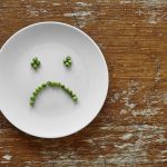 sad hungry smiley face out of peas on plate